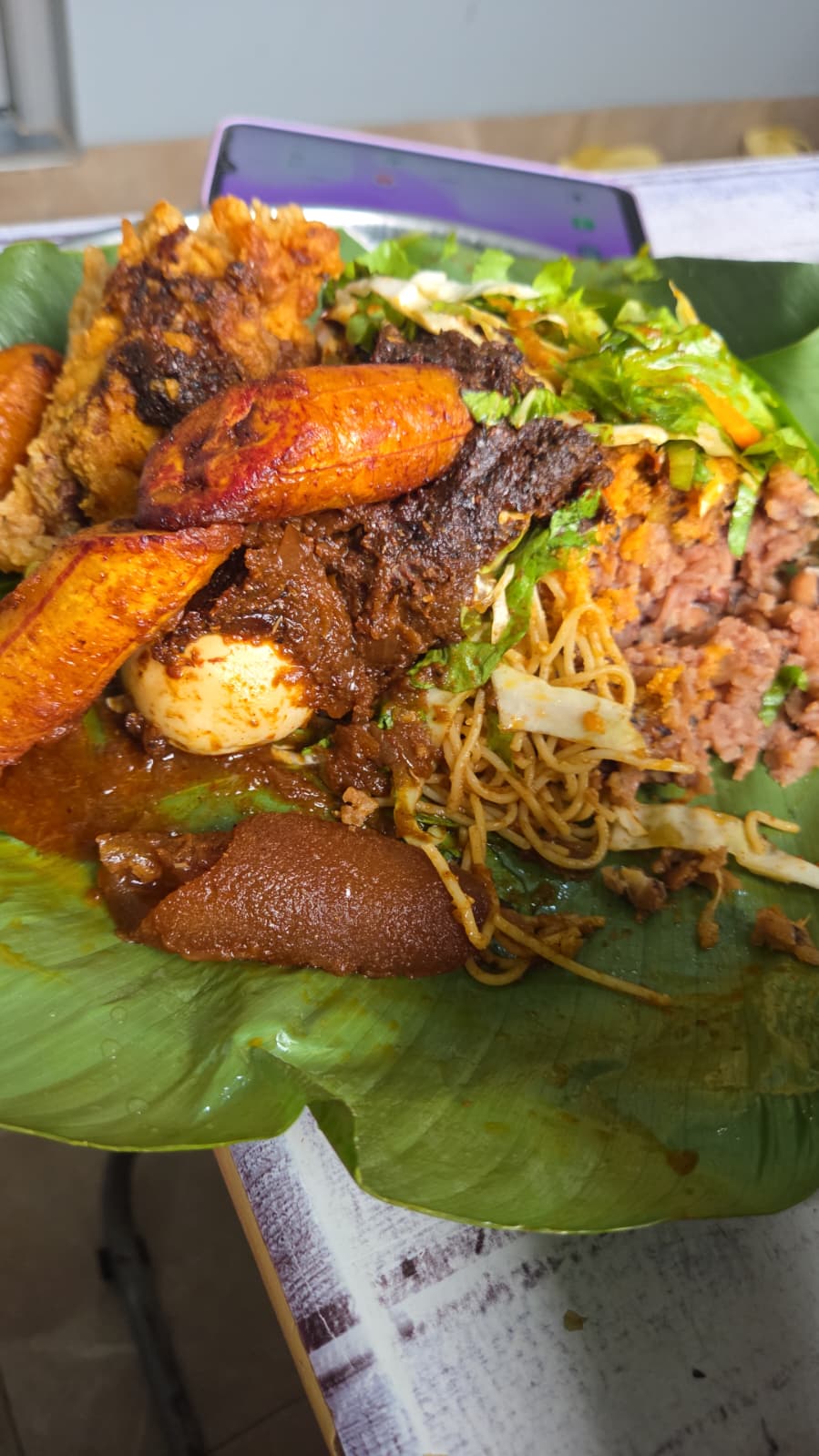 Ghanaian waakye served with plantain, meat, egg, noodles and salad