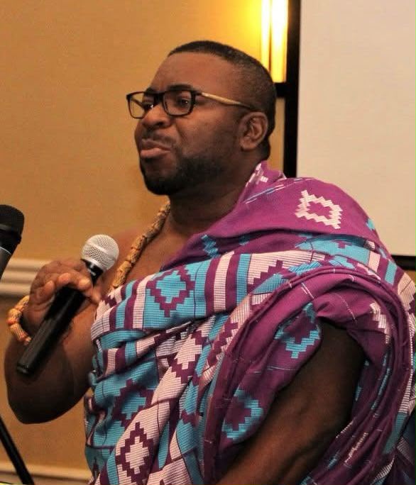 Ghanaian man speaking into a microphone while wearing traditional attire