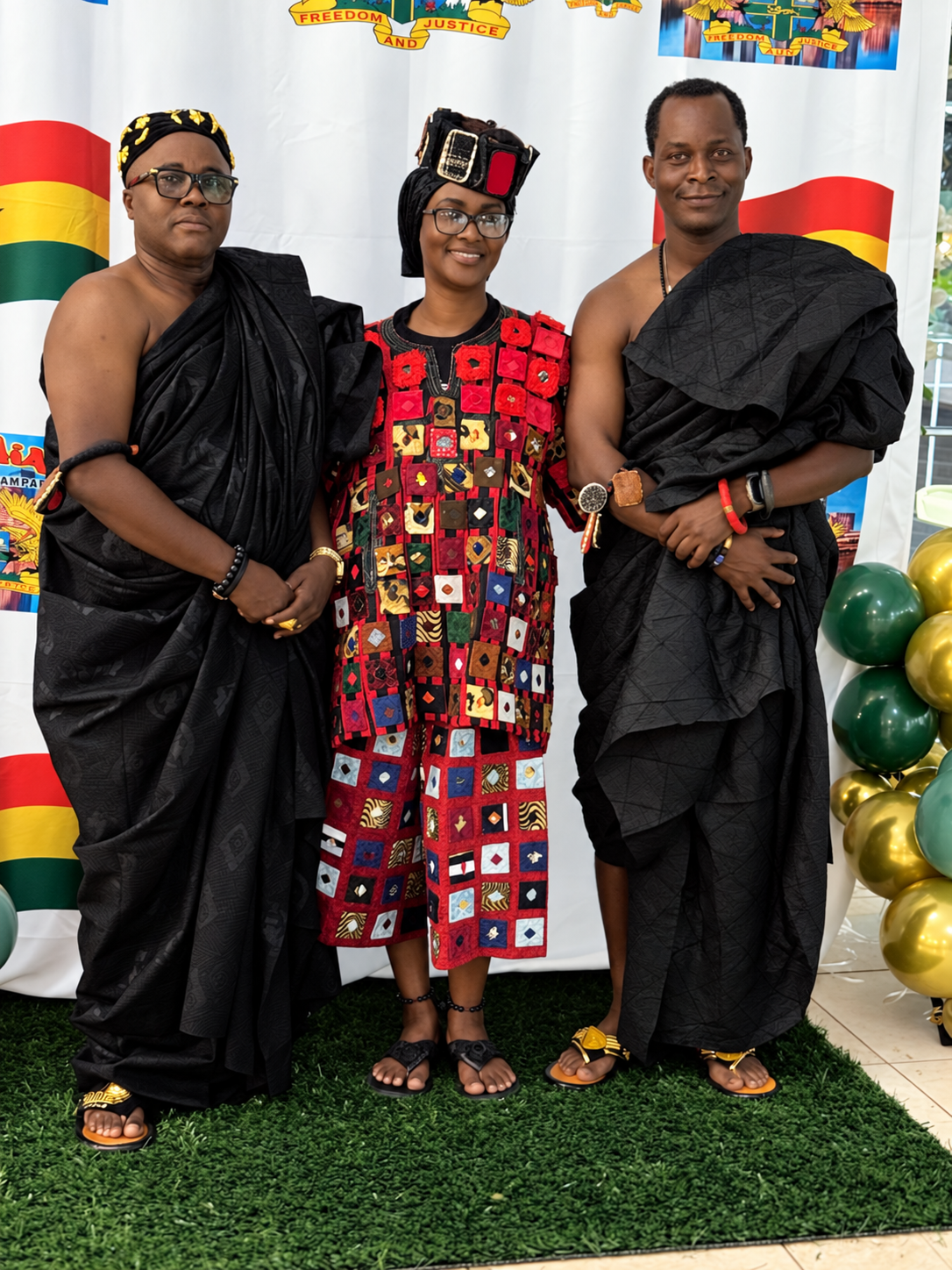 Three community members wearing Ghanaian traditional attire at a cultural celebration